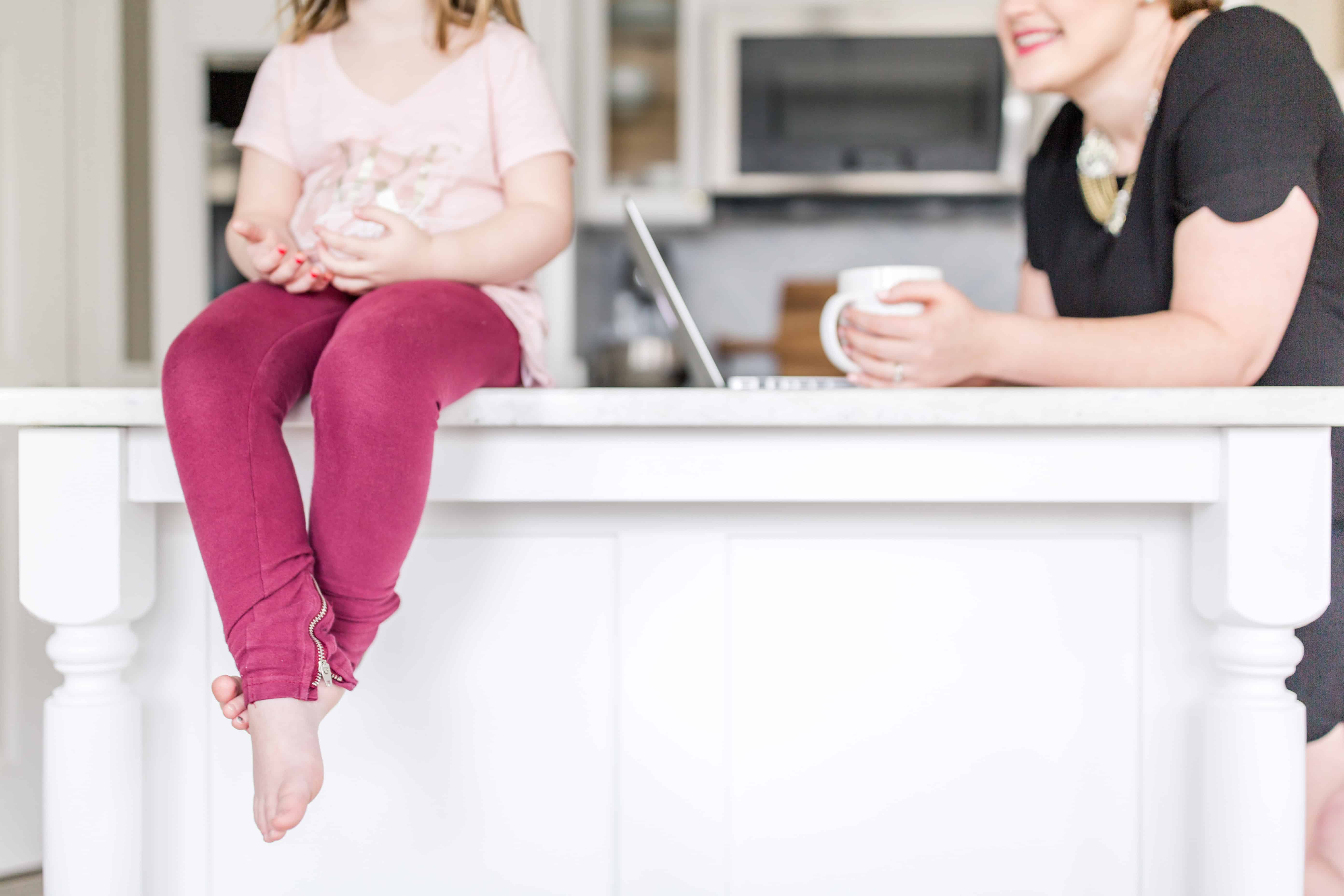 Toddler eating donut sitting on counter next to mom