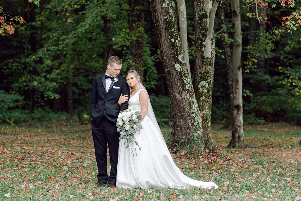 a newlywed couple linking arms under a tree
